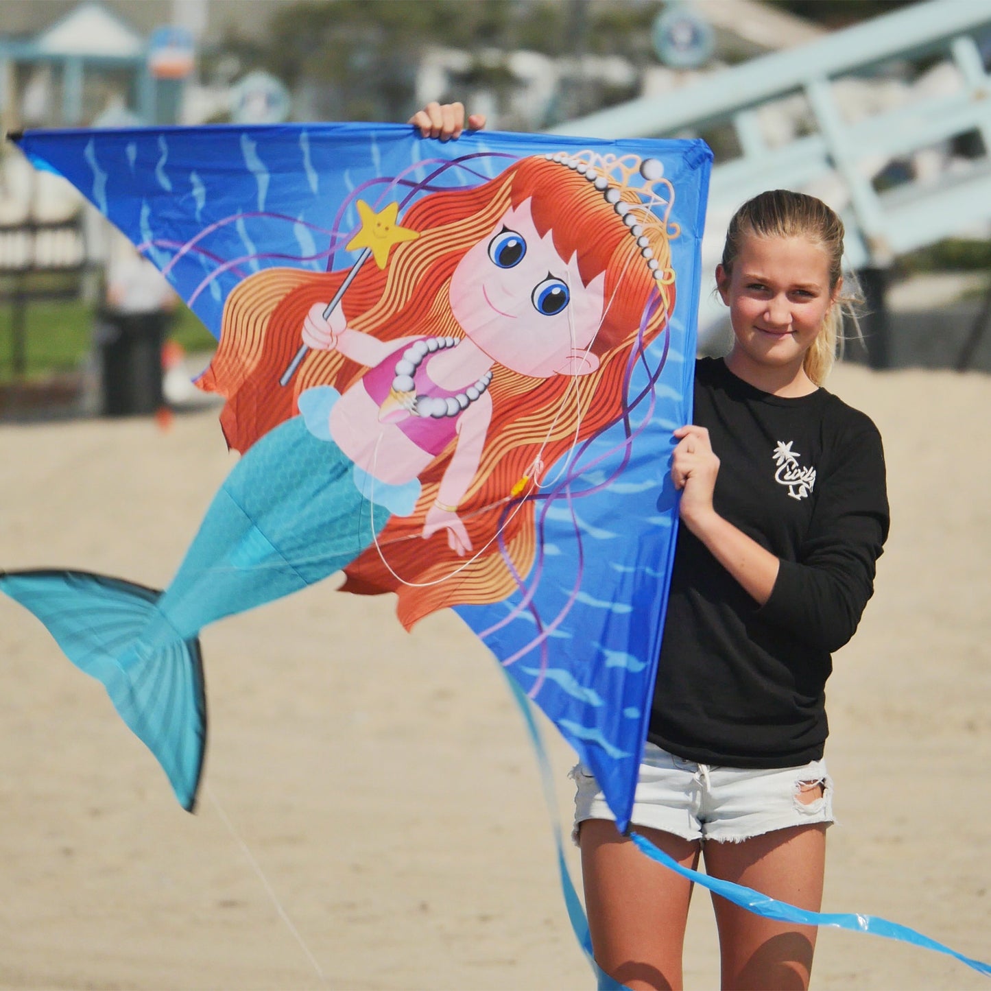 girl holding mermaid kite at the beach