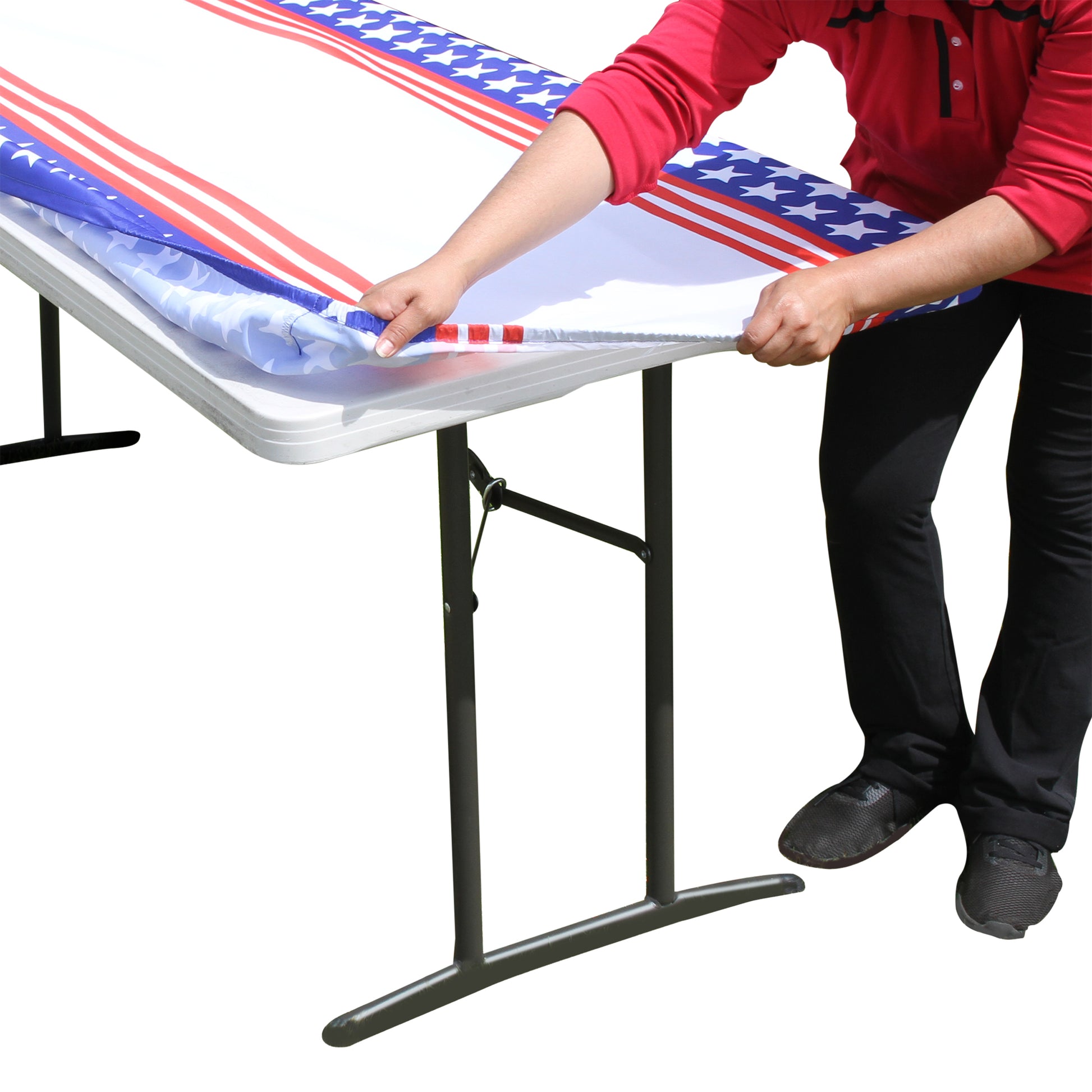 A person stretching TableCloth PLUS 72" Stars & Stripes Fitted Polyester Tablecloth for 6' Folding Tables over a folding table