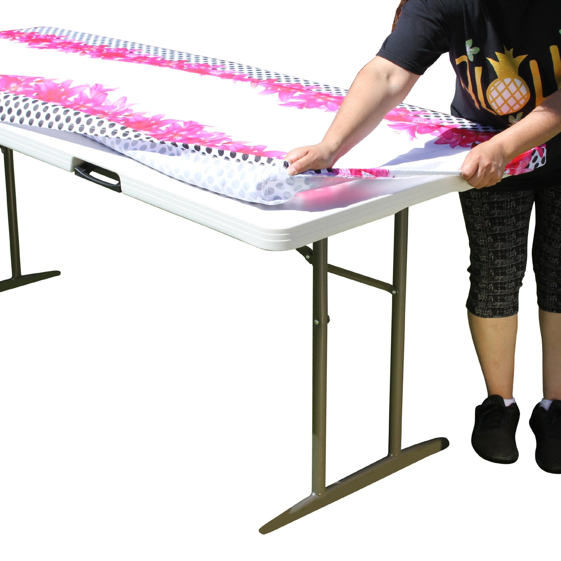 A person stretching TableCloth PLUS 72" Lilies Fitted Polyester Tablecloth for 6' Folding Tables over a folding table