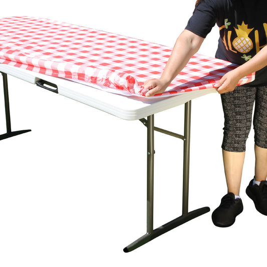 A person stretching TableCloth PLUS 72" Checkerboard Red and White Fitted Polyester Tablecloth for 6' Folding Tables over a folding table